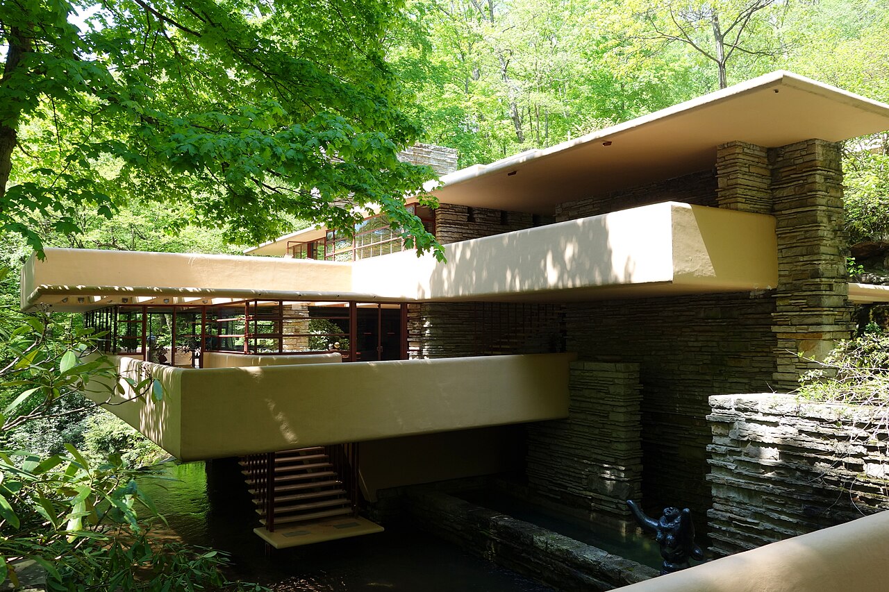 Fallingwater terraces and suspended stair above Bear Run, with stone piers and trees surrounding the house.